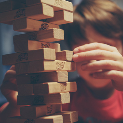 A boy carefully sliding out a block from a Jenga tower
